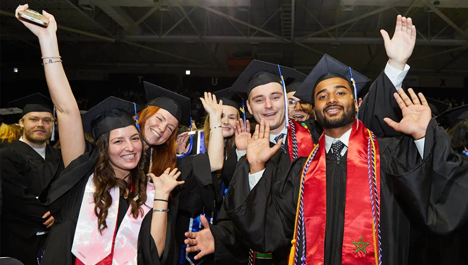 A group of five students pose together in their graduation regalia