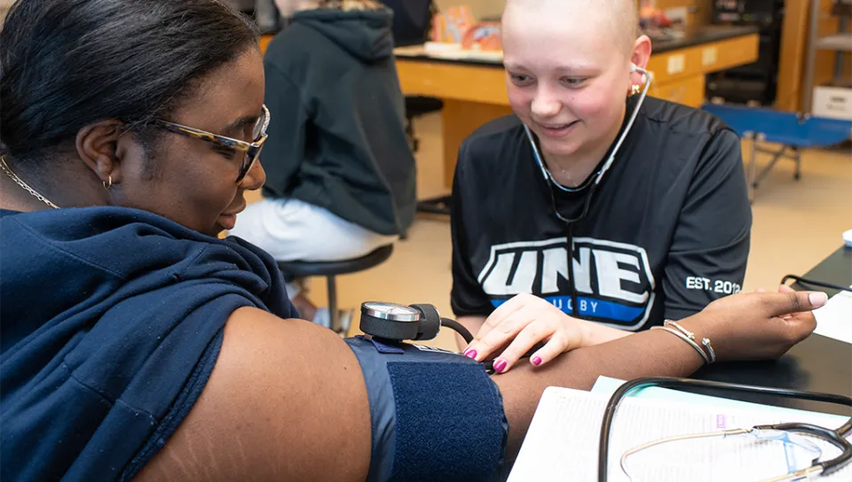 A student uses a stethoscope to listen to the heartbeat of another student via their inner elbow