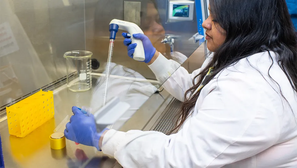 A student in a white coat extracts liquid