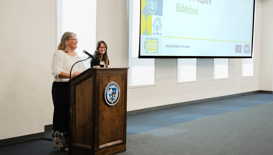 Nonprofit leader Delilah Poupore speaks at the podium with Sustainability Fellow Miranda Carrabba