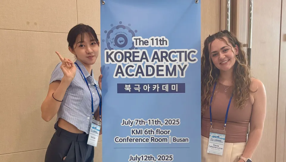 Shauna and her roommate pose in front of a Korea Arctic Academy banner