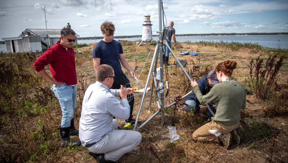 A UNE research team secures the weather station to the island