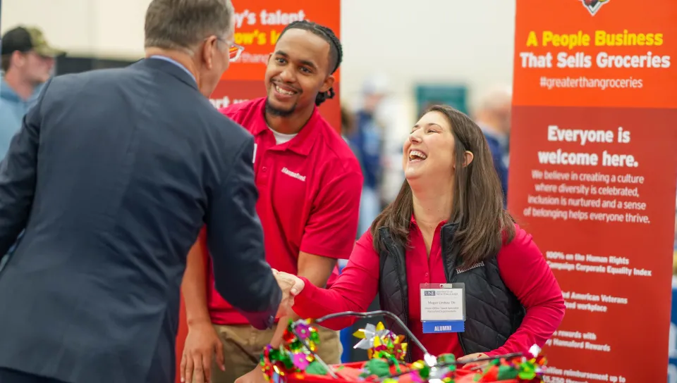 A UNE alum with the Hannaford supermarket chain shakes hands with UNE President James Herbert
