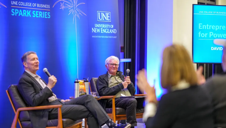 James Herbert speaking into mic to David Shaw