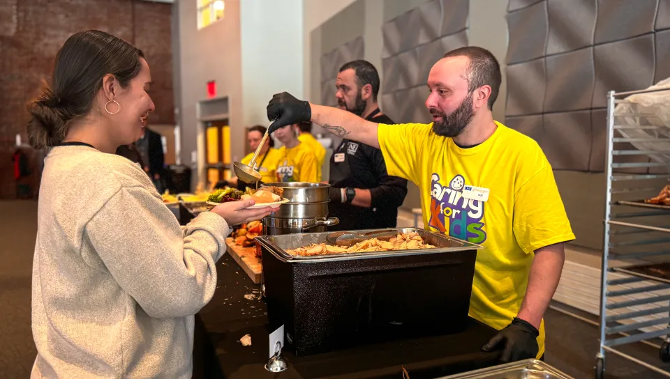 A UNE dining services worker serves a student at a luncheon