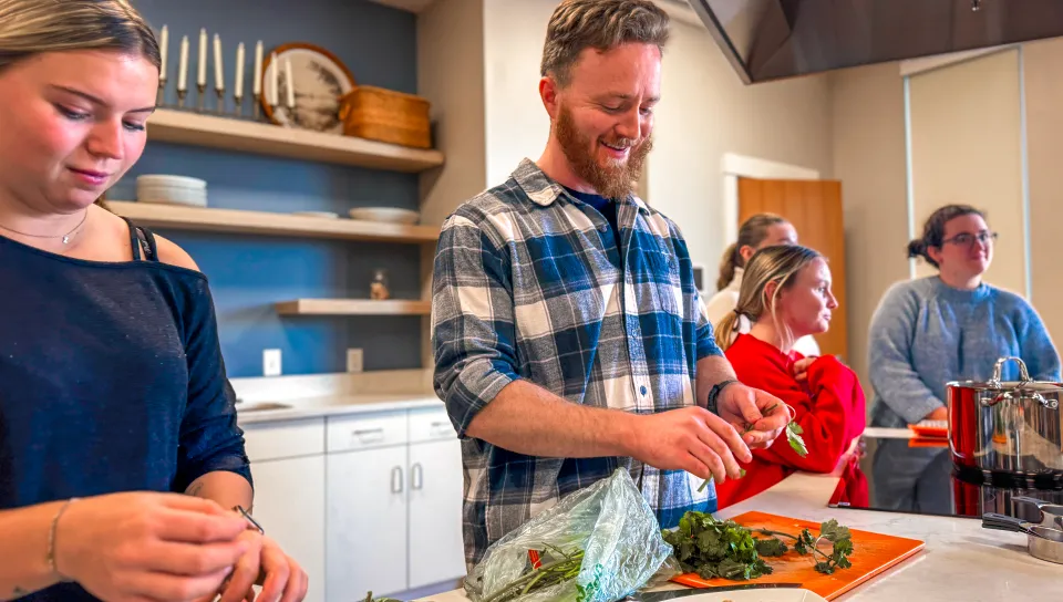 A UNE student smiles while preparing meal ingredients