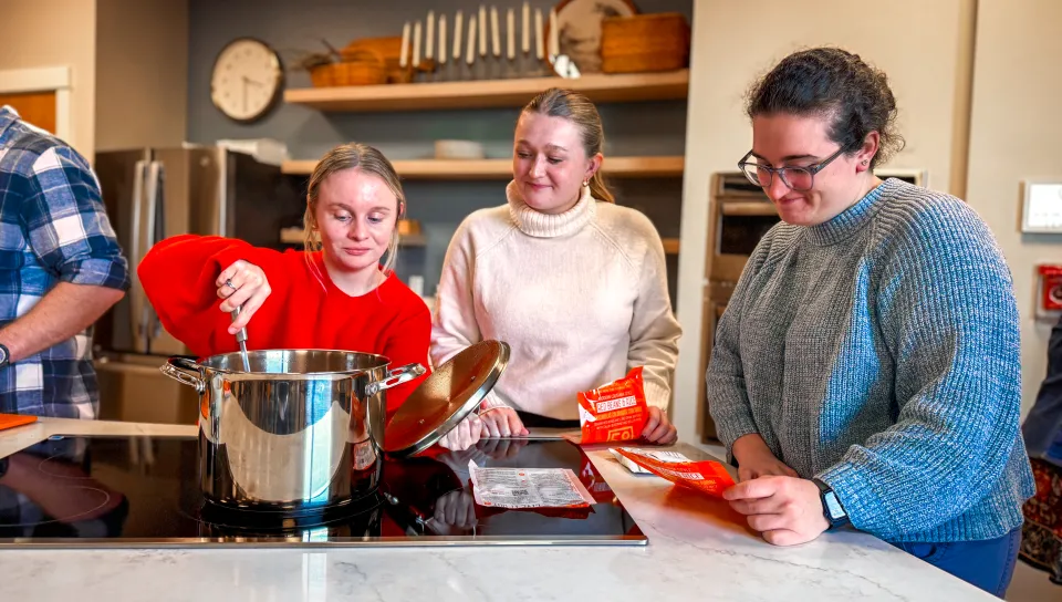Students stir a pot on the kitchen stove