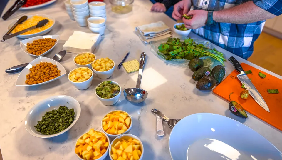 An assortment of fruits, vegetables, herbs, and toppings prepared for meal service