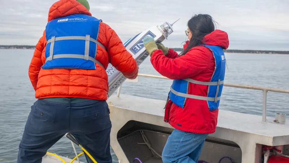 UNE student Jasmin Townsend-Ng (’26) assists Dr. Kochtitzky in lower a buoy