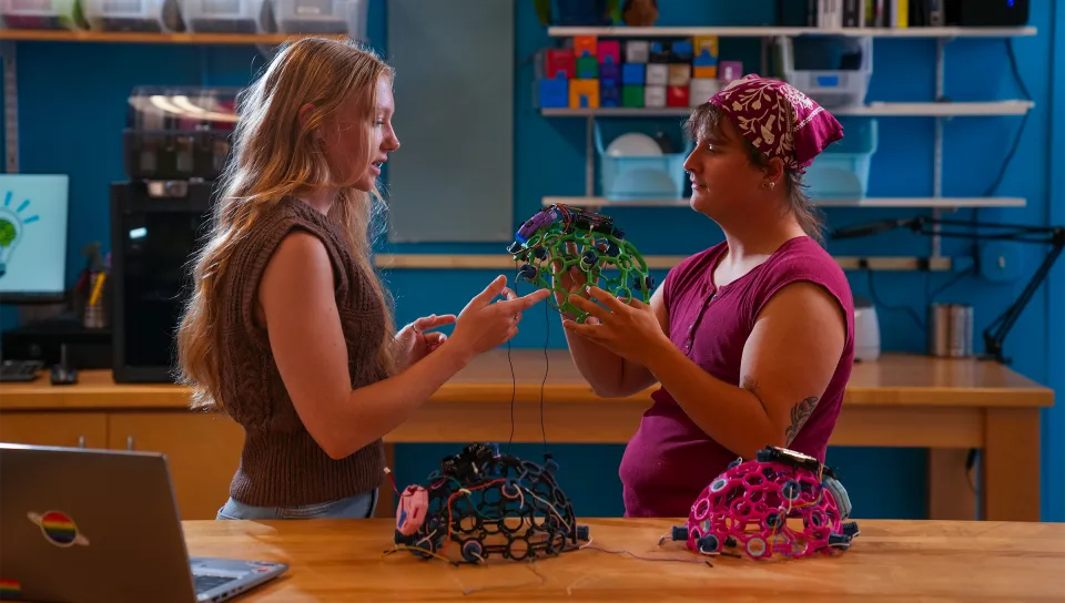 Jessica Howard and Milo Lypps hold a green brainwave cap.