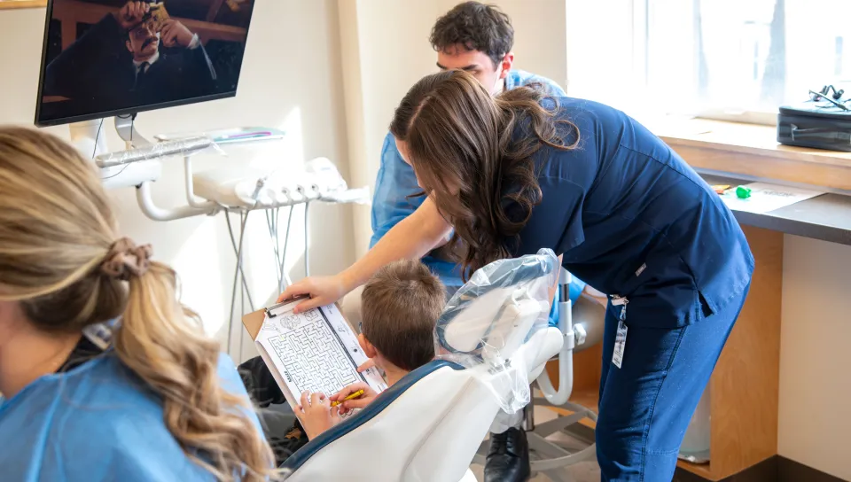 A UNE dental medicine student provides activities for a pediatric patient