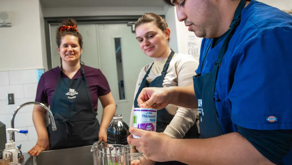 A team of students adds a commercial thickener to a blended mixture