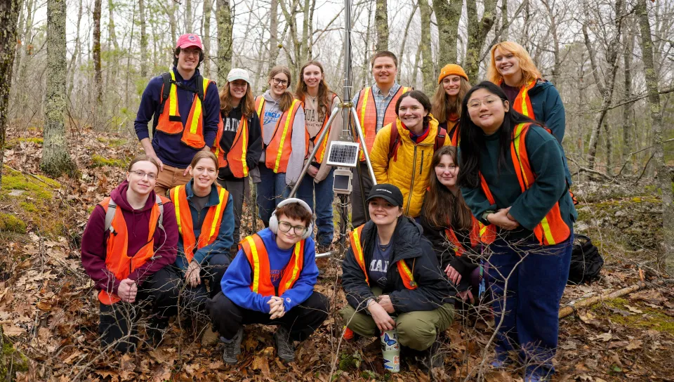All researchers pose for a group shot in the forest
