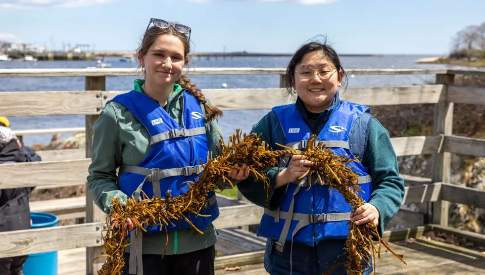 Two students pose with a strand of kelp