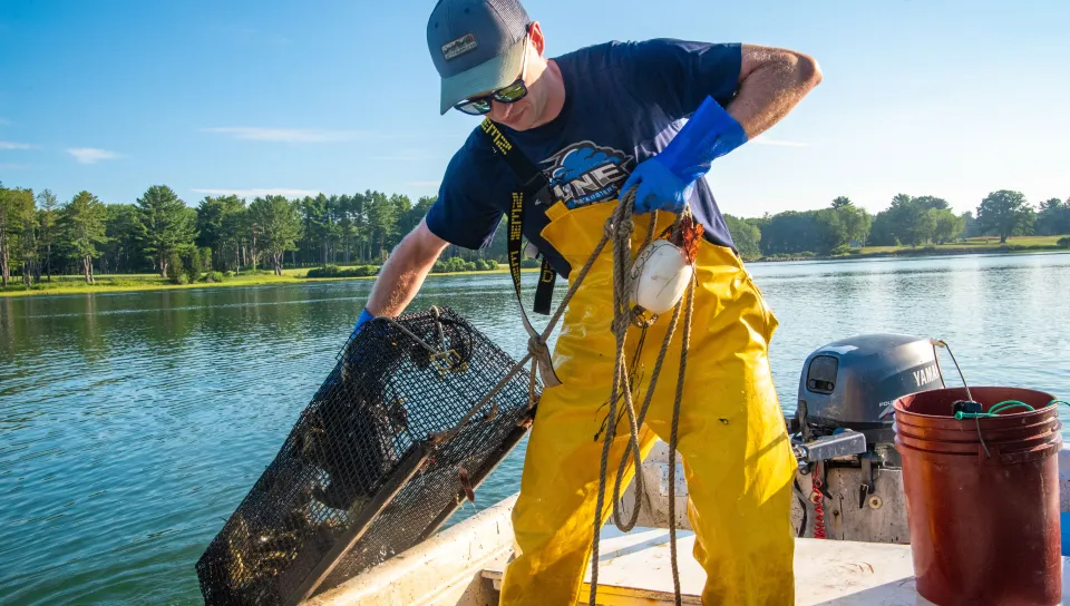 Jackson Martine hauls a green crab trap out of the water