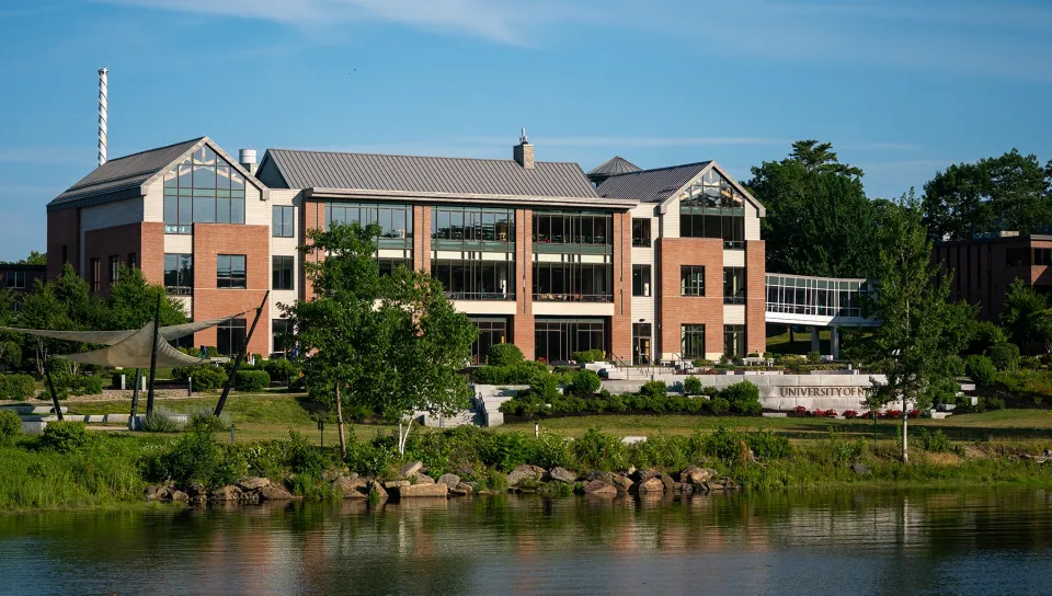 The Commons building at U N E's Biddeford Campus, reflected in the water at golden hour on a summer evening.
