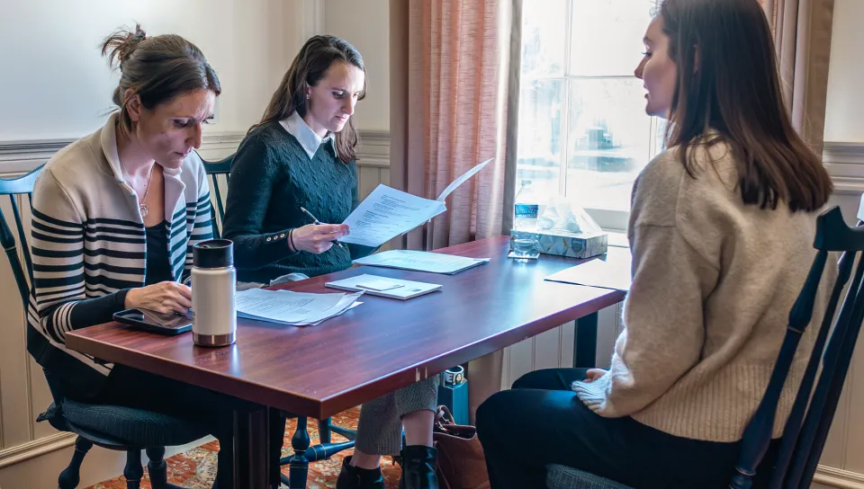 A U N E Pharmacy student participates in a mock interview seated across from two interviewers reviewing her resume.