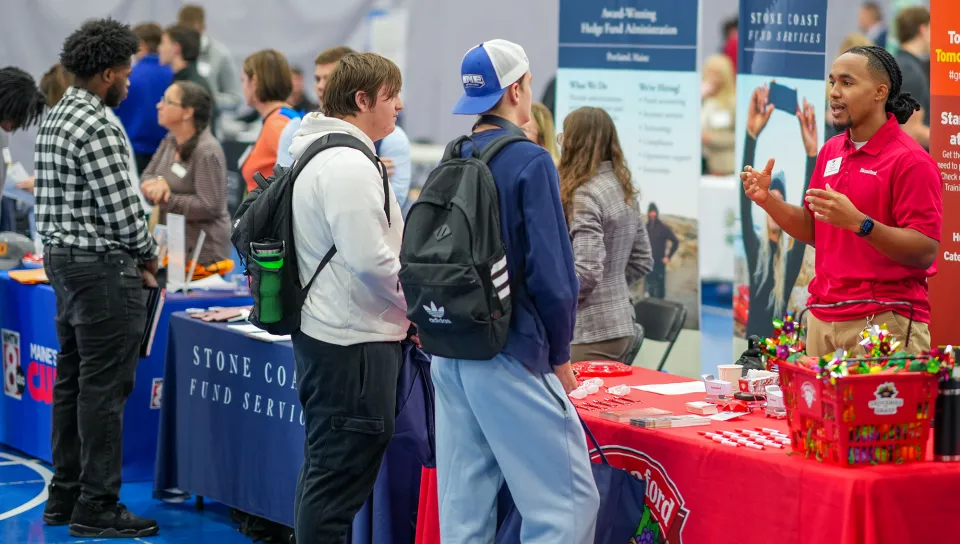 U N E students talk with an employer representative at a booth during Industry Exploration Day.