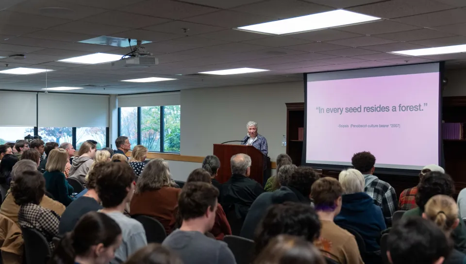 An audience listens to poet Mikhu Paul speak
