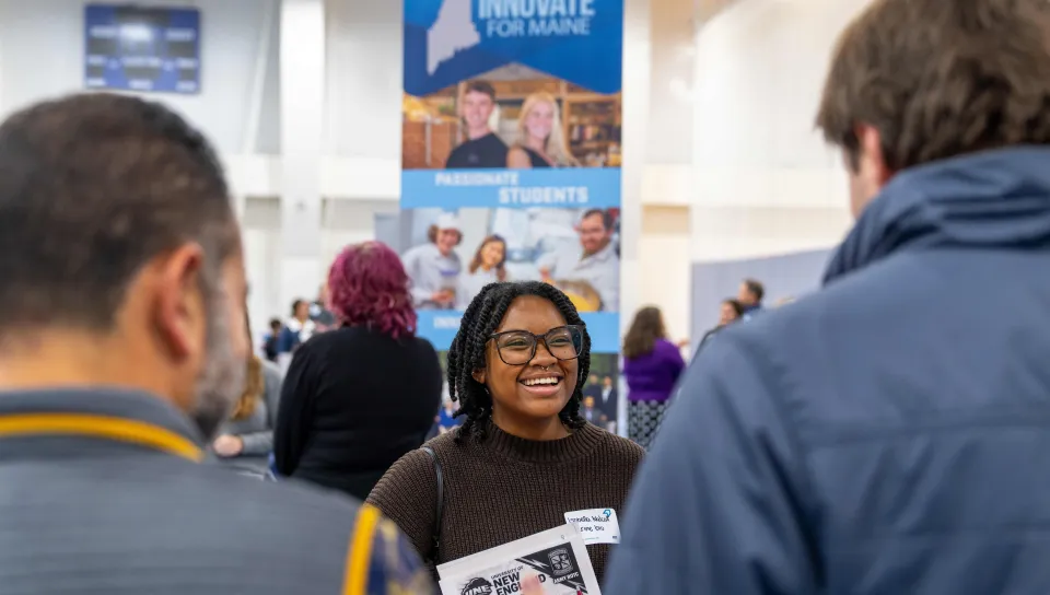 A student smiles while speaking with employers at a job fair