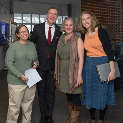 President Herbert and three other individuals standing together in a hallway