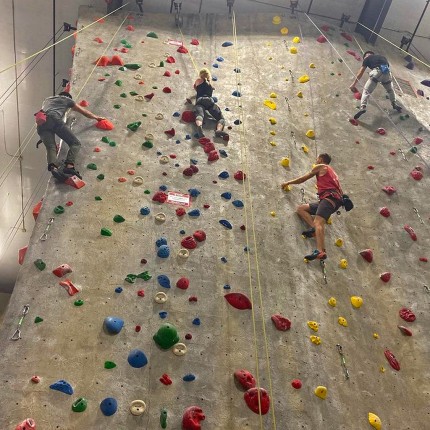 Three students climbing an indoor rock wall