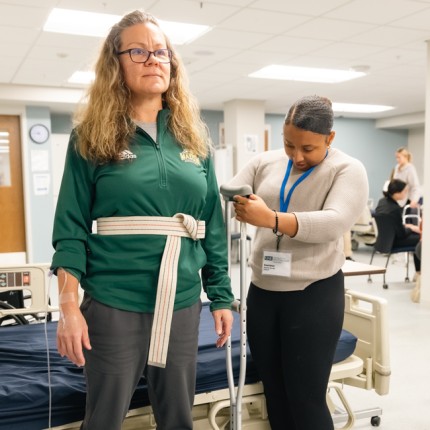 A P T student practices measuring a crutch for a patient