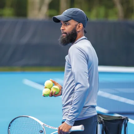 Coach Jovan Jordan-Whitter prepares to serve tennis balls during practice at UNE's outdoor tennis facility on Old Pool Road in Biddeford.