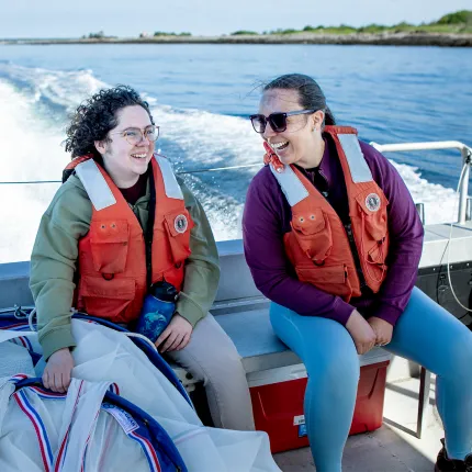 Two students in life vests laughing together on a boat
