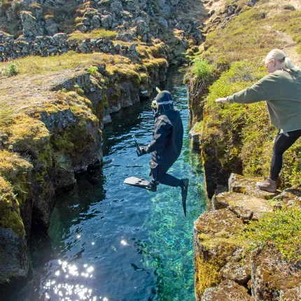 A U N E student in a dry suit leaps into a glacial fissure to snorkel in Iceland.