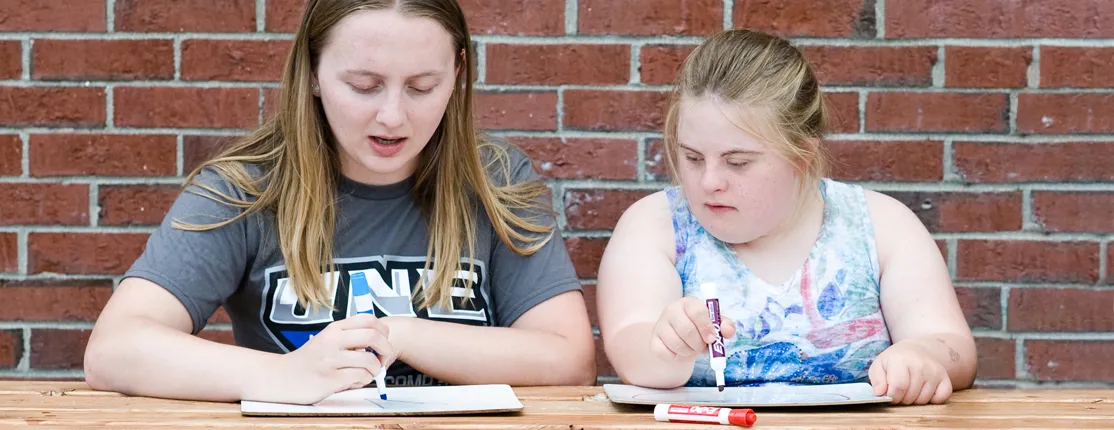 A special education major draws with a middle school student
