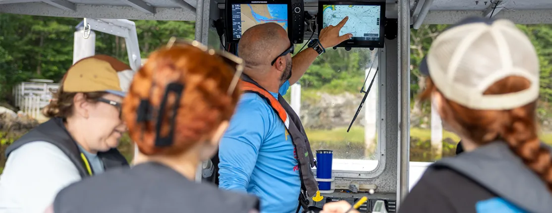 Students on boat looking at navigation screens while instructor points
