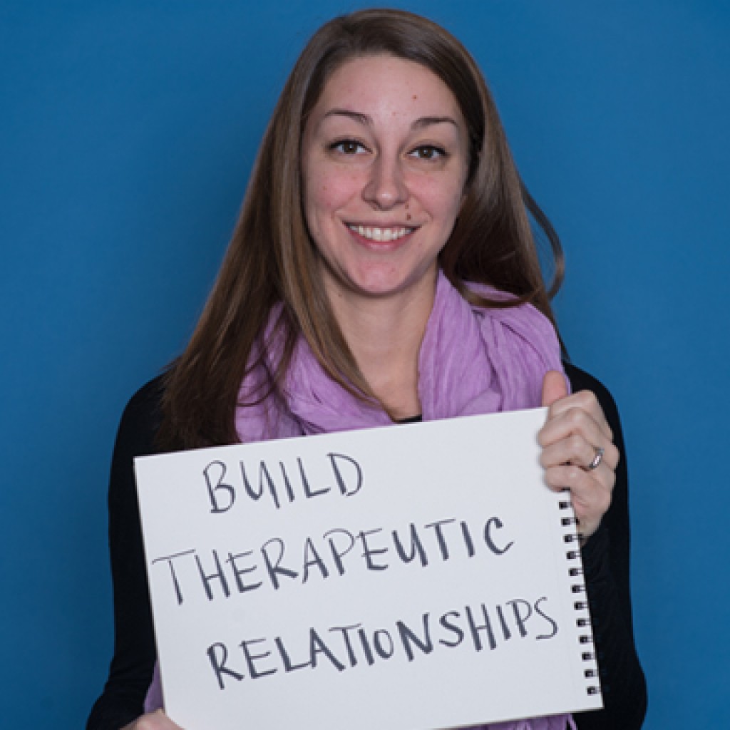 a u n e social work student holds a handwritten sign reading build therapeutic relationships