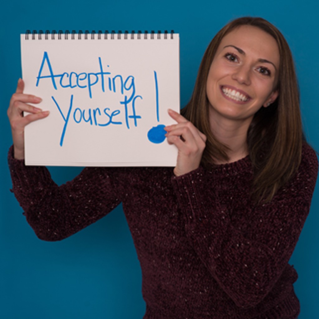 a u n e social work student poses with a handwritten sign reading accepting yourself