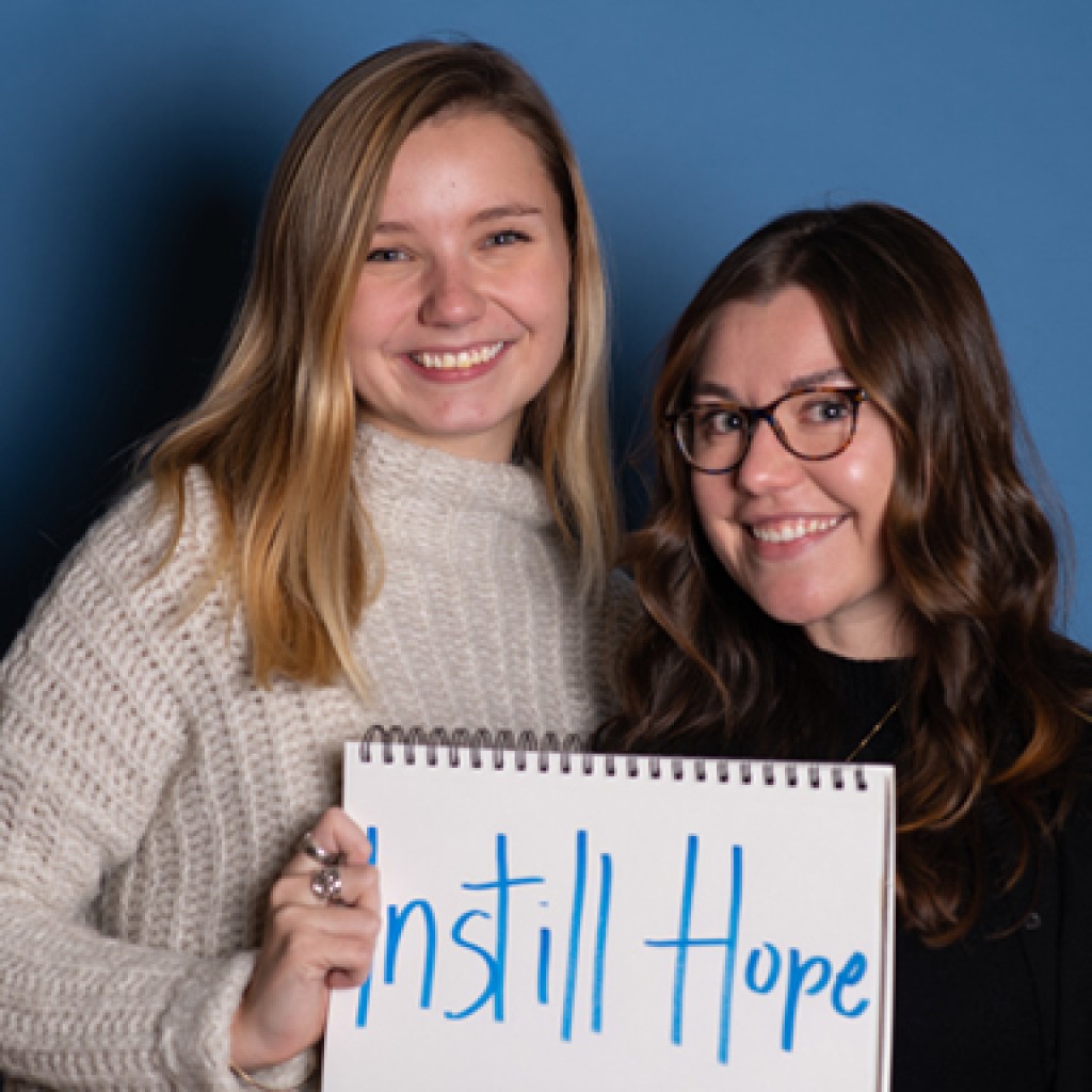 two u n e social work students pose with a handwritten sign that reads instill hope