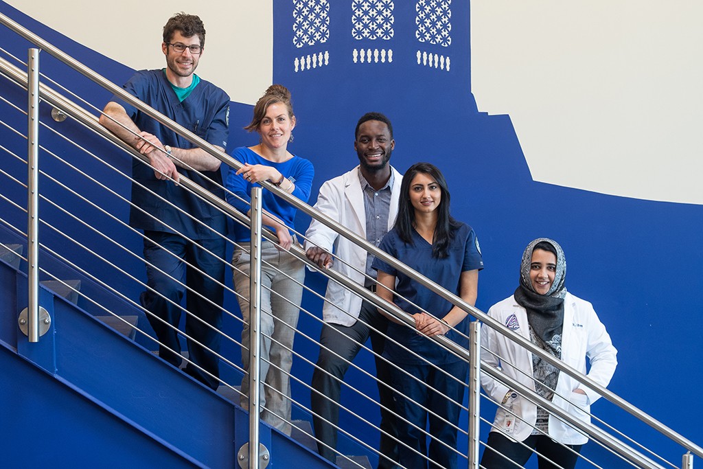 Five U N E health professions student pose together on a staircase