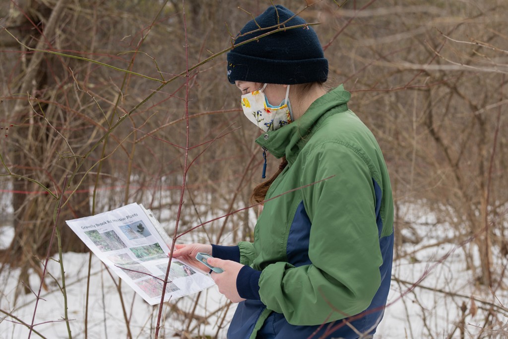 A student standing outside in the snow examines a informational flyer about birds