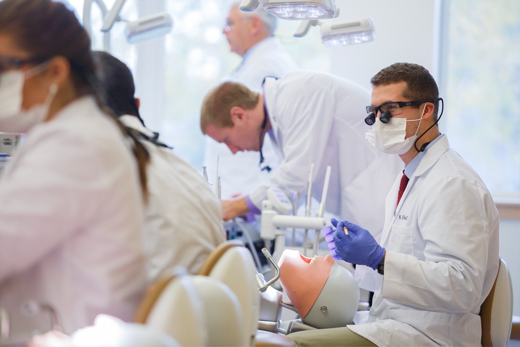 A dental student works on a patient simulator