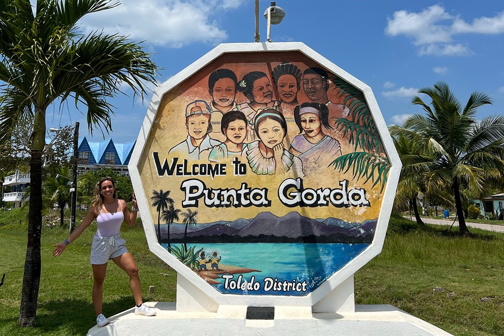 Ana Maria Castellanos standing in front of a sign that says "Welcome to Punta Gorda"