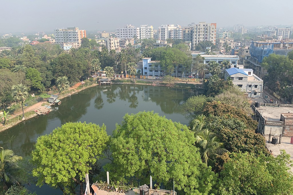 Trees and water against a cityscape in Tangail