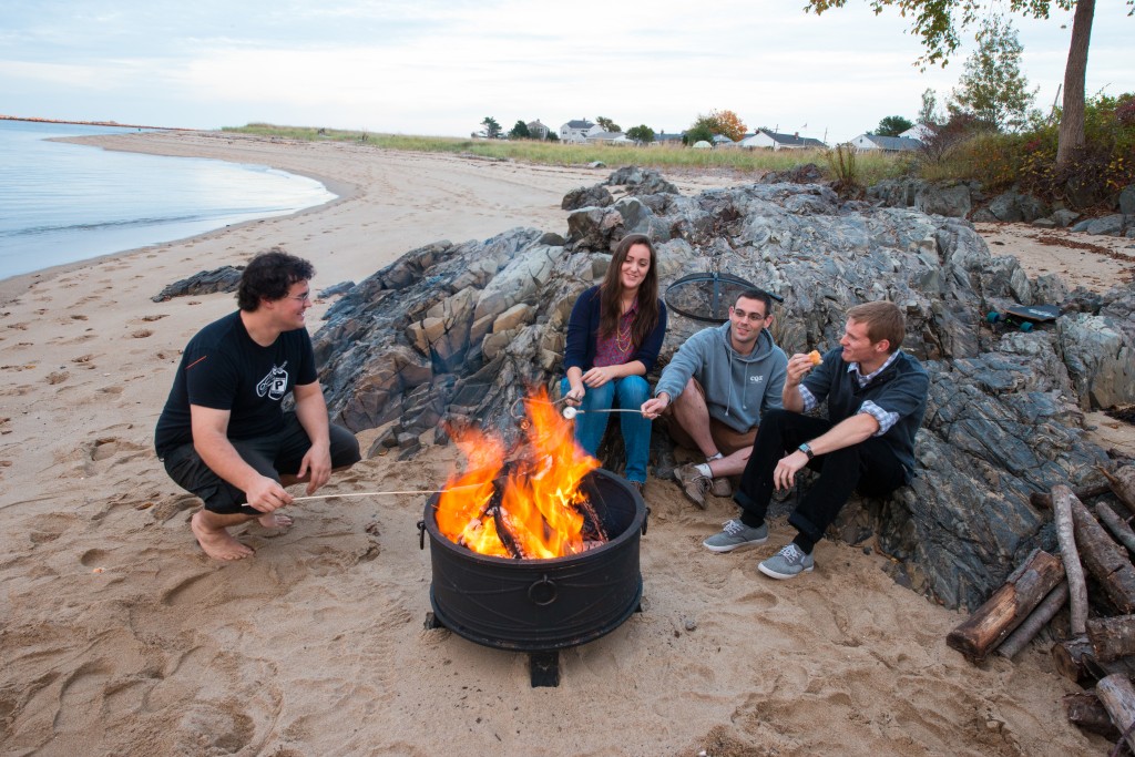 UNE students sit around a campfire on the beach