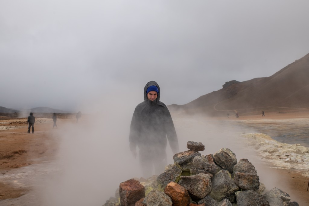 A student walks through dense fog on a rocky landscape