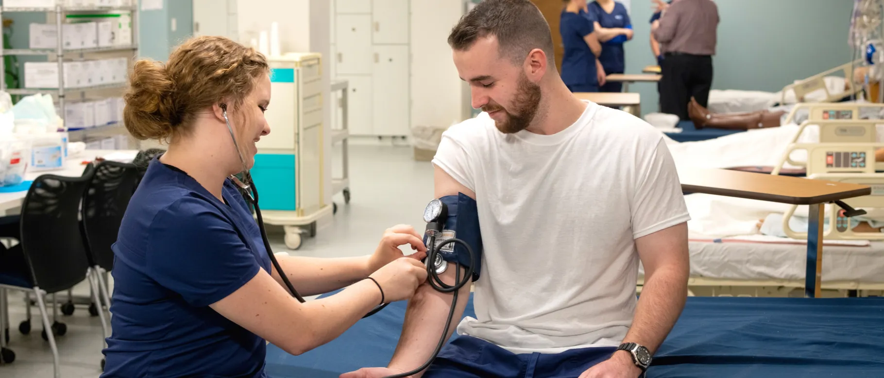 A nursing student takes another student's blood pressure in UNE's Interprofessional Simulation and Innovation Center