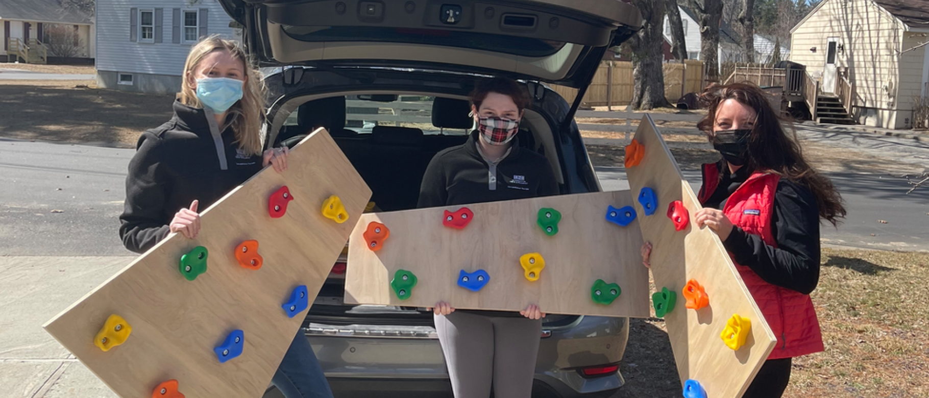 Students hold pieces of a climbing wall they made for a project