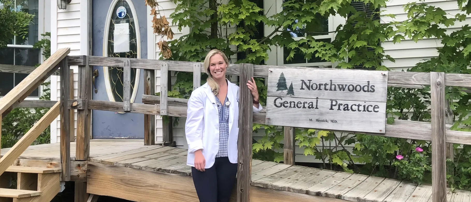 Woman stands in front of health care facility, smiling