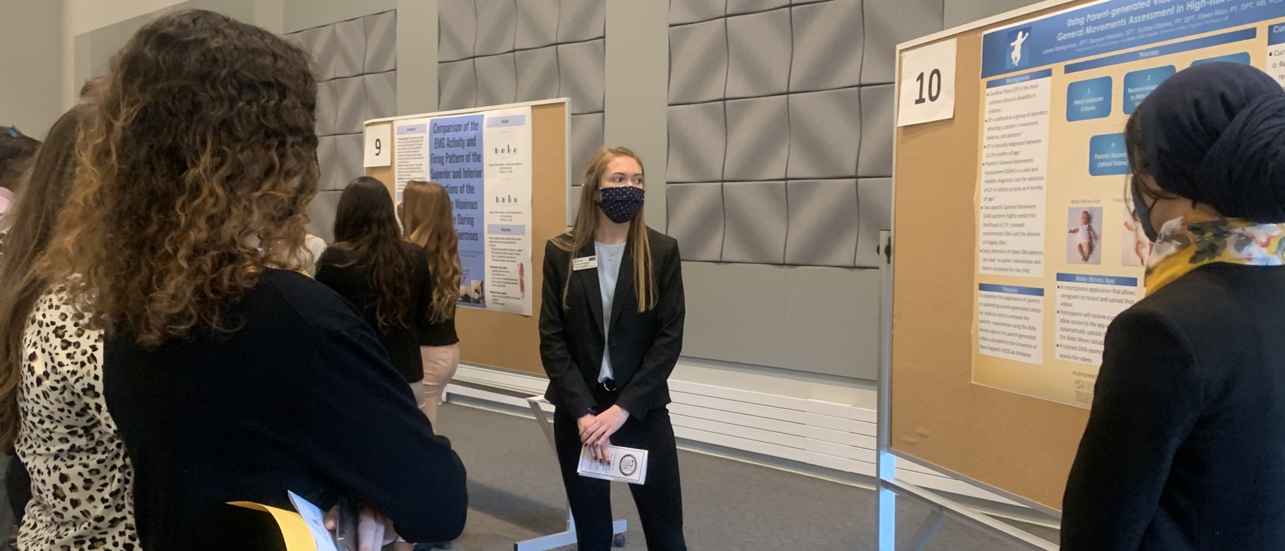 Female student presents research poster to small crowd