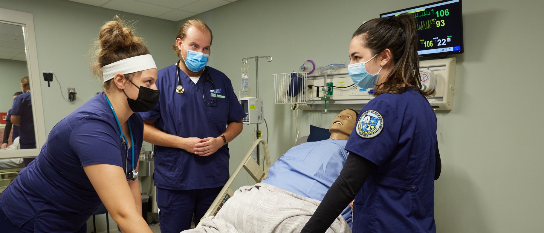 Nursing students stand around a patient simulator in UNE's Interprofessional Simulation and Innovation Center
