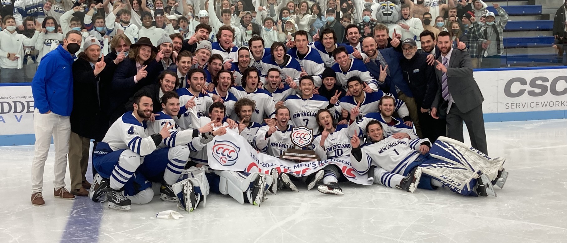 A large crowd of students and ice hockey players pose on the ice after the Nor'easters men's ice hockey team won the CCC championship