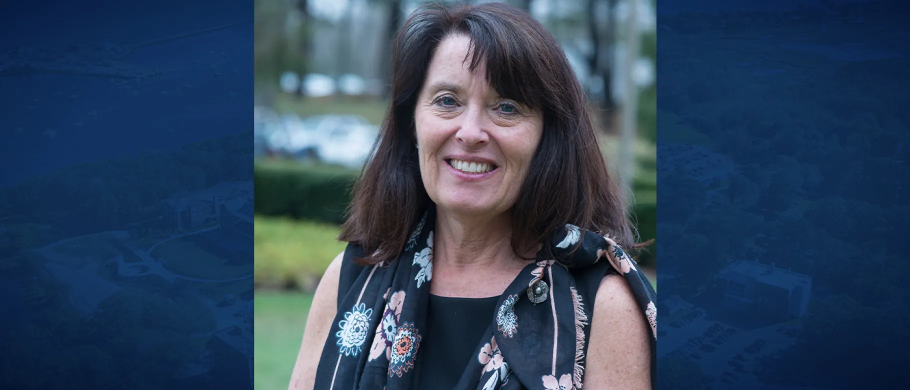 UNE registrar Kathy Davis smiles for a portrait against the quad