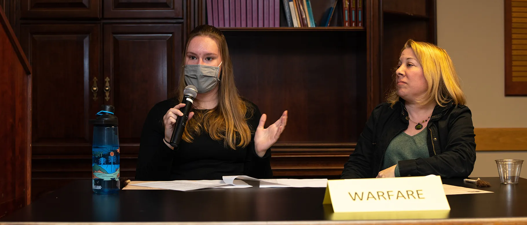 Meghan Hanks speaks at the debate while teammate Candace Baker looks on.